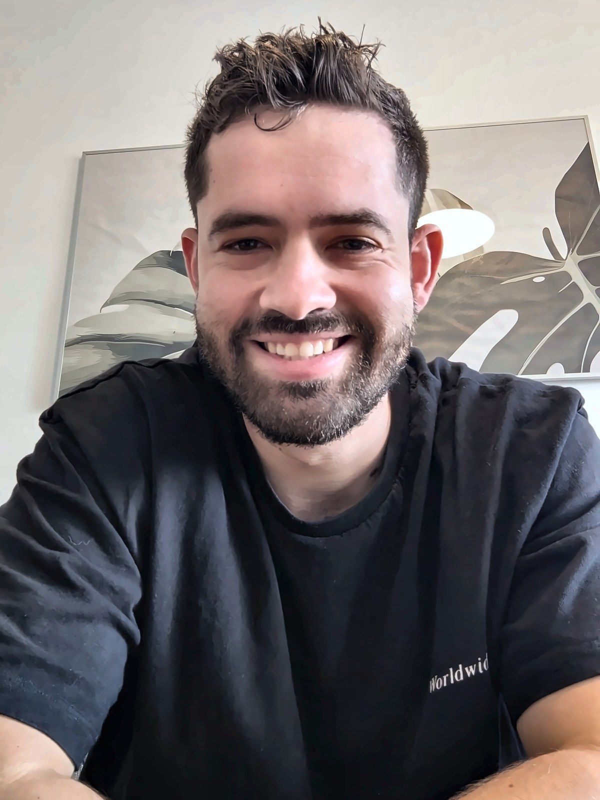 תומר מחייך למצלמה מהבית, כמו בתחילת שיחת וידאו