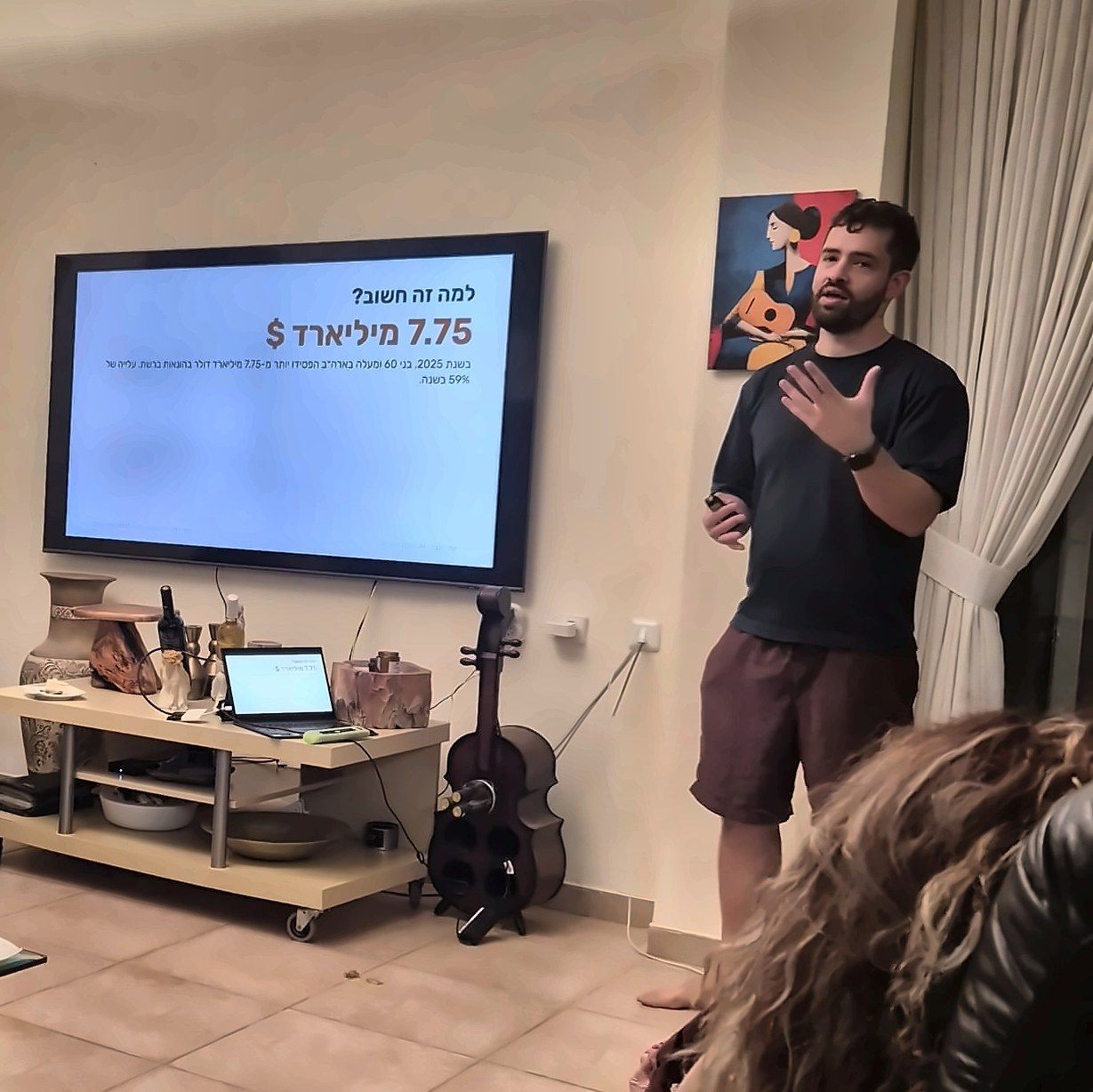 תומר מרצה מול קהל בסלון, ליד מסך עם שקף על הונאות ברשת